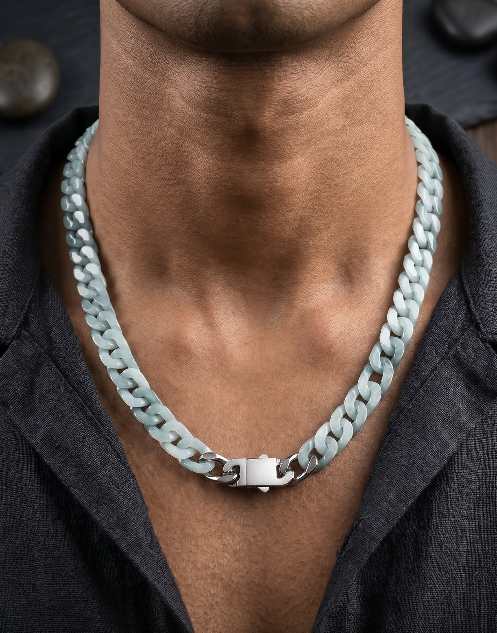 A close-up of a man's neck and chest wearing a chunky, light blue-gray real jade chain necklace with a silver clasp, paired with a dark gray shirt.