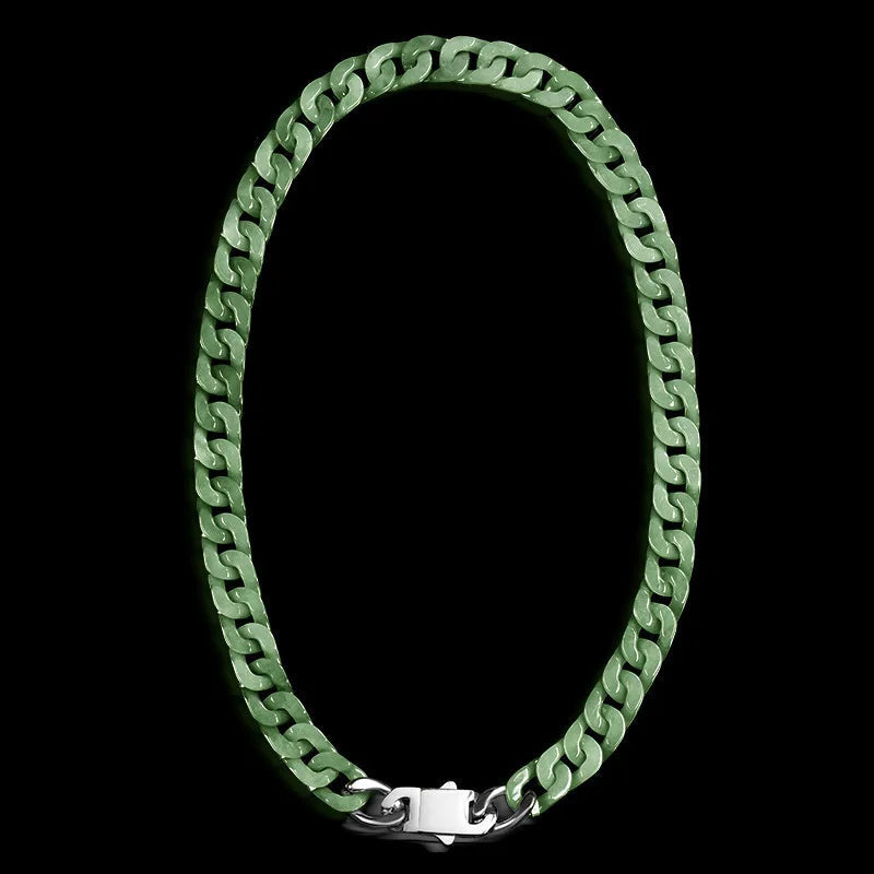 A green Jade cuban link chain necklace with a silver clasp, displayed in an oval shape against a solid black background. 
